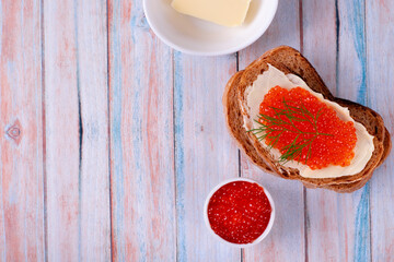 Sandwich with red caviar and butter on blue wooden table. Top view. Mockup with copy space