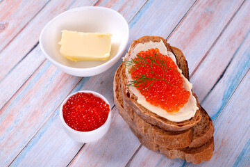 Sandwich with red caviar and butter on blue wooden table