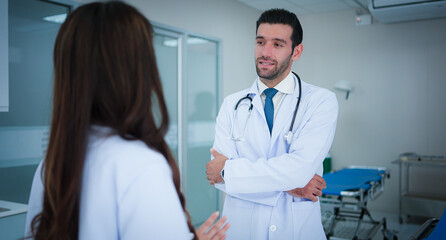 Two professional medical, Male doctor and asian female doctor colleague at work standing talk discuss about medical and patient in ward at hospital.