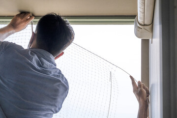 technician worker man install plastic net for protect pigeon bird in balcony apartment