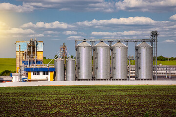 Agricultural Silos. Storage and drying of grains, wheat, corn, soy, sunflower against the blue sky with white clouds.Storage of the crop.