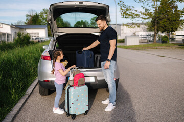 Father help daughter loading to the trunk with luggage before traveling while mom packs her luggage
