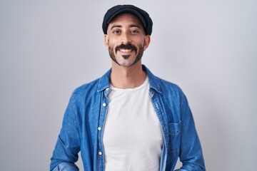 Hispanic man with beard standing over isolated background with hands together and crossed fingers smiling relaxed and cheerful. success and optimistic