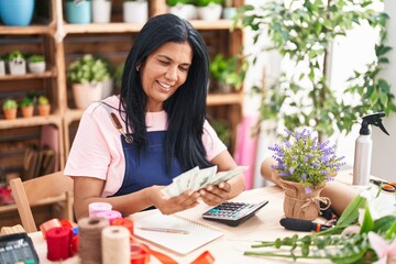 Middle age hispanic woman florist smiling confident counting dollars at florist