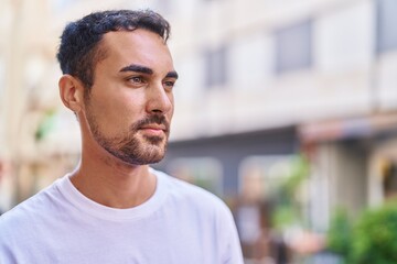 Fototapeta premium Young hispanic man looking to the side with serious expression at street