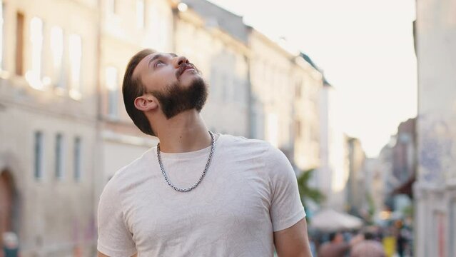 Portrait of bearded young man tourist walking in urban city street background in summer sunshine daytime. Guy traveler smiling having positive good mood enjoying outdoors. Town lifestyles, vacation