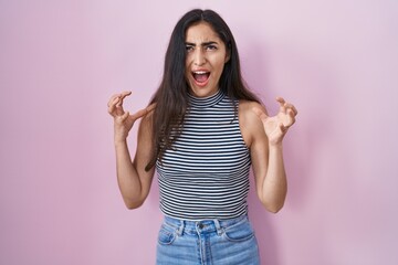 Young teenager girl wearing casual striped t shirt crazy and mad shouting and yelling with aggressive expression and arms raised. frustration concept.