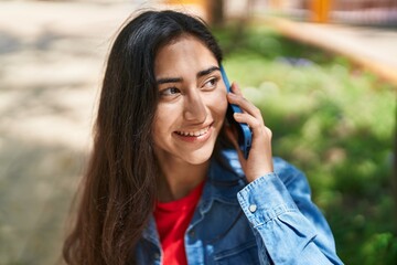 Young hispanic girl smiling confident talking on the smartphone at park