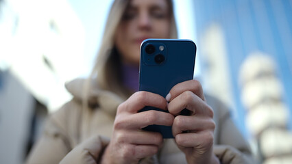 Young blonde woman using smartphone at street