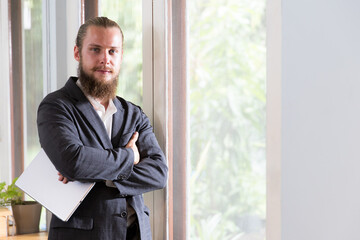 Fototapeta premium Bearded young businessman holding a tablet and looking at camera with confidence