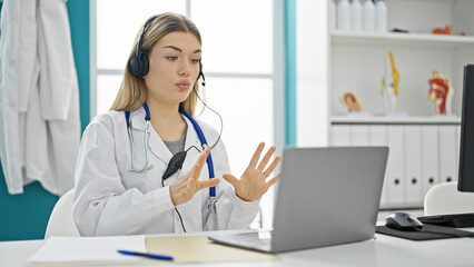 Young blonde woman doctor on video call at clinic