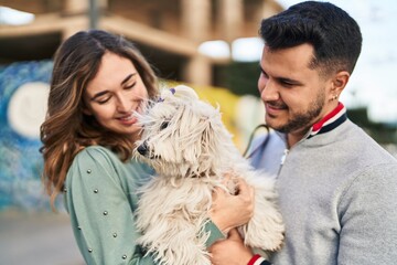 Man and woman holding dog standing together at street