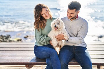 Man and woman holding dog hugging each other at seaside