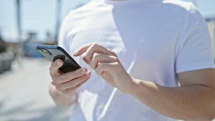 Young hispanic man using smartphone with serious expression at street