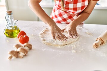 Obraz na płótnie Canvas Young beautiful hispanic woman kneading dough pizza with hands at the kitchen