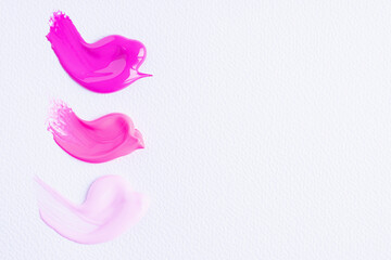 Three smears of different pink paint swatch on white paper background. Bright pink, pink and light pink swatch of lip gloss, cosmetic product stroke or paint