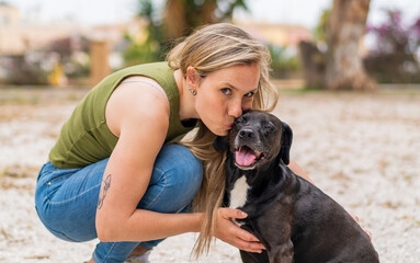 Young blonde woman at outdoors with her adorable black dog