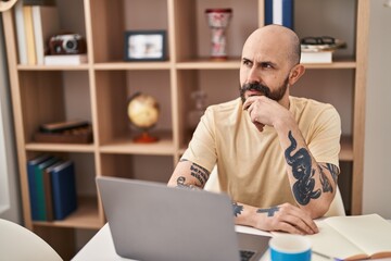 Young bald man using laptop sitting on table at home