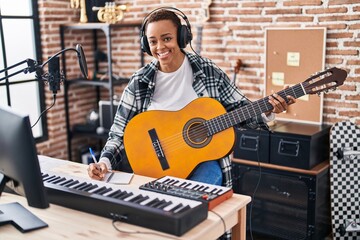 African american woman musician composing song playing classical guitar at music studio