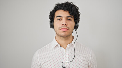 Young latin man business worker wearing headphones over isolated white background - obrazy, fototapety, plakaty