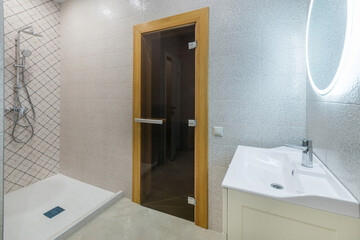 A small room in the SPA, with a shower and sink. Glass entrance door to the sauna.