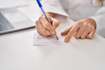 Young beautiful hispanic woman doctor writing on covid certificate card at clinic