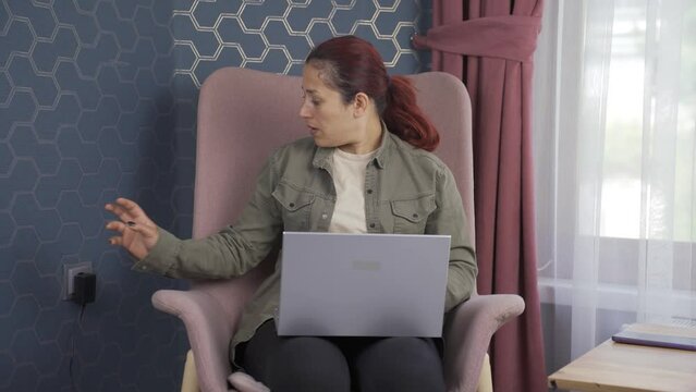 The woman unplugs the charger from the outlet.