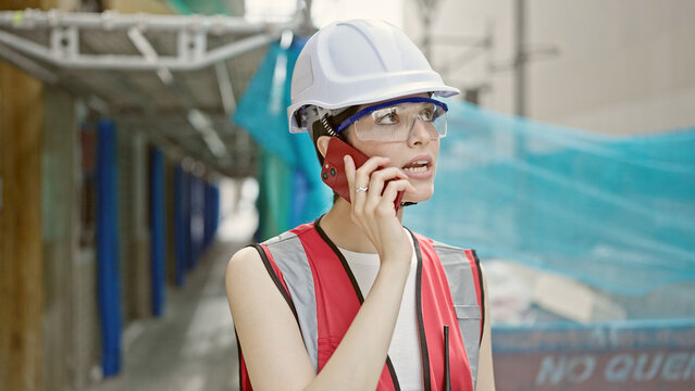 Young beautiful hispanic woman builder talking on smartphone at street