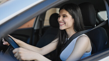 Obraz na płótnie Canvas Young beautiful hispanic woman smiling confident driving car at street