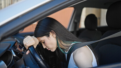 Fototapeta na wymiar Young beautiful hispanic woman stressed sitting on car at street