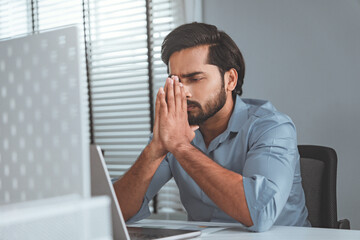Naklejka premium Stress, Serious Indian male frustrated with work sitting in front of a laptop. Mental health, headache or depressed corporate worker with frustrated fail or bad error