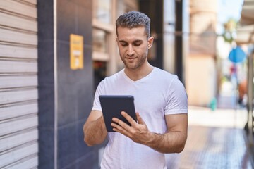 Young caucasian man using touchpad with relaxed expression at street