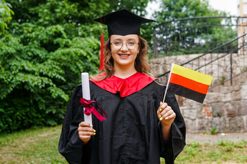 Young german woman wearing graduation gown and hat holding flag of Germany smiling happy and...