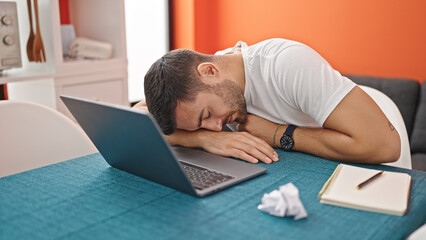 Young hispanic man sleeping on table at dinning room