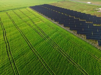 Amazing aerial view of a solar power plant at sunset, featuring rows of panels in the midst of a vibrant green landscape, emphasizing the importance of eco-friendly energy production.