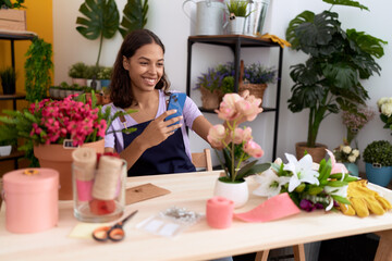 Young african american woman florist smiling confident make photo to flowers at flower shop