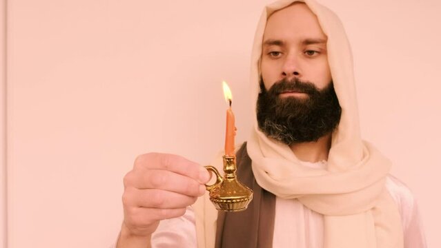 close-up bearded man in image of Savior holding burning candle, Jesus Christ, concept religious ceremony, biblical scene of Holy Scriptures of Old and New Testaments, Christian religion