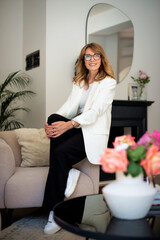 Full length of an attractive middle aged woman relaxing in an armchair in a modern home