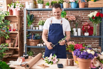 Young hispanic man florist cutting stem of flower at florist