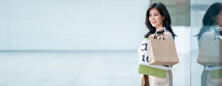 Panoramic Cheerful Asian Business Woman Shopaholic Girl Carrying Shopping Bag  While Walking In Shopping Mall. Lifestyle Of People On Weekend.