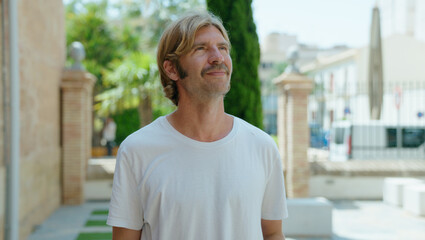 Young blond man with relaxed expression standing at street