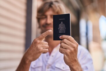 Young man smiling confident pointing with finger to passport at street