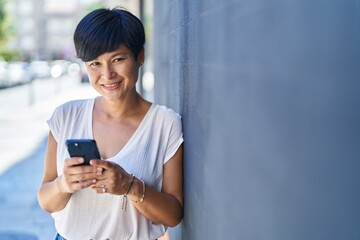 Middle age chinese woman smiling confident using smartphone at street