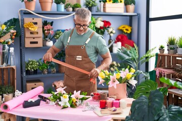 Middle age grey-haired man florist holding lace at flower shop