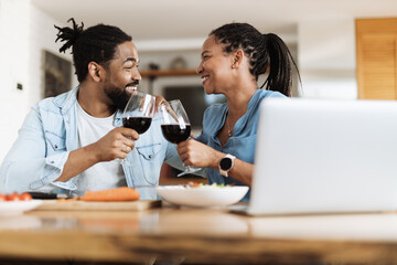 Happy African American couple toasting with wine during lunch at dining table