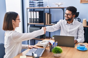 Man and woman business workers smiling confident shake hands at office
