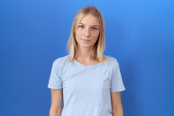 Young caucasian woman wearing casual blue t shirt relaxed with serious expression on face. simple and natural looking at the camera.