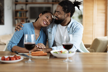 Obraz na płótnie Canvas Happy black couple embracing during a meal in dining room