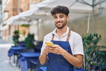 Young arab man waiter using smartphone working at restaurant