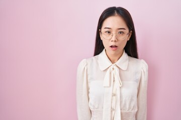 Young chinese woman standing over pink background afraid and shocked with surprise expression, fear and excited face.